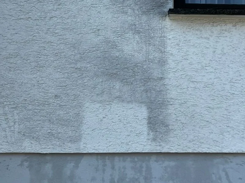 Heller, gereinigter Probefleck in einem dunkel vergrauten Streifen der Putzfassade